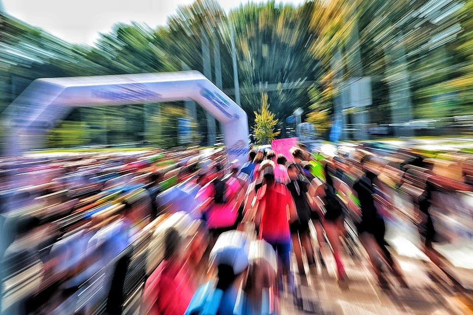 Pole běžců pod startovní branou, rozostřené tahem transfokátoru