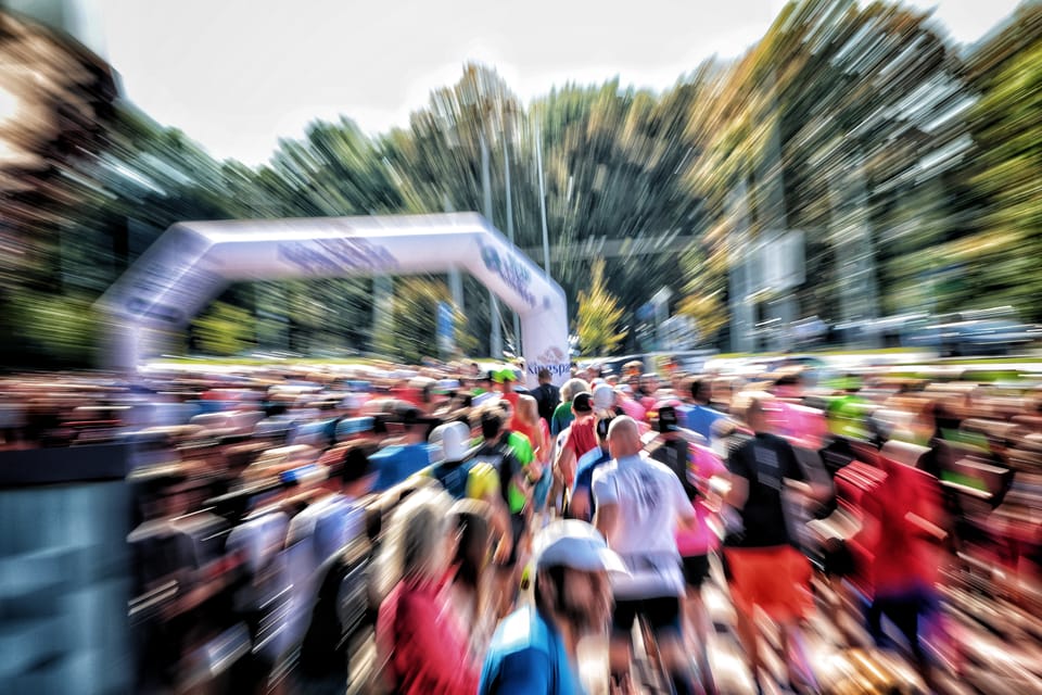 Pole běžců pod startovní branou, rozmáznuté tahem transfokátoru do paprsků