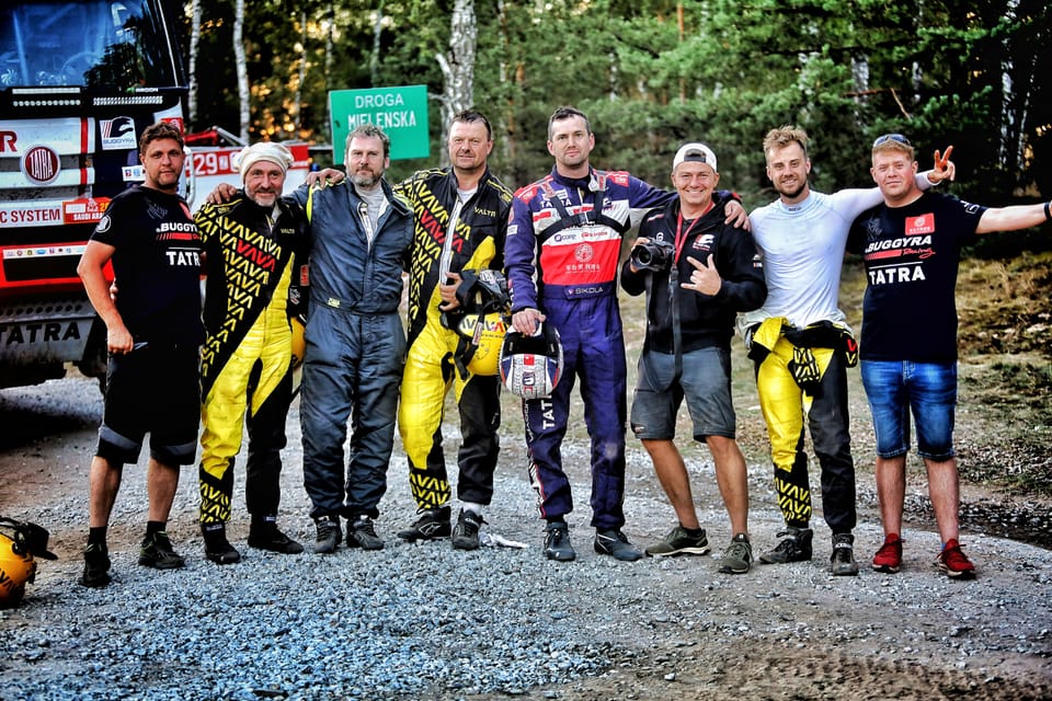 A team lined up along a forest road, overalls in yellow and black
