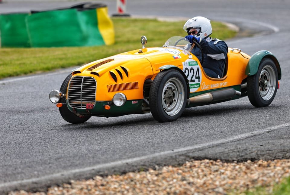 A yellow and green open-top veteran, number 224, leaning into a bend