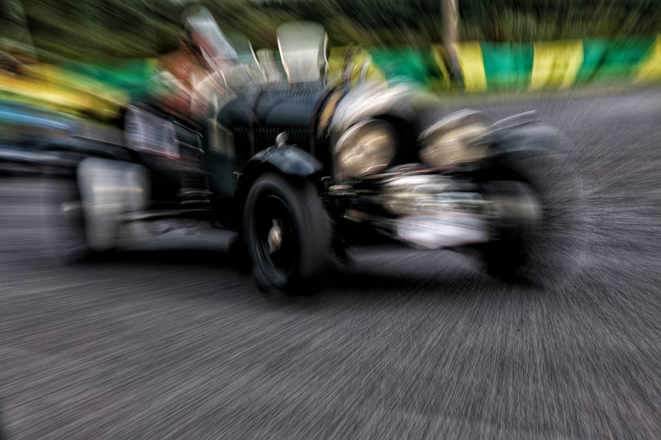 Předválečný závodní vůz vytržený rozostřením pohybem, okolí se kolem něj stáhlo do paprsků