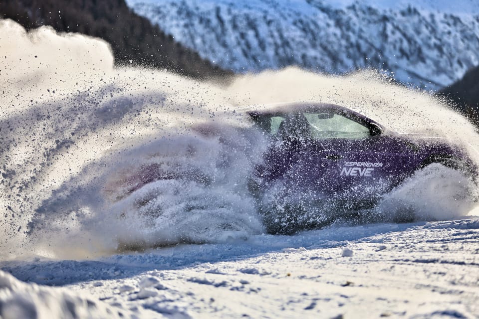 A car disappearing into a fan of thrown snow, only its windows left visible